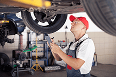 Man working with automotive inspection equipment with car on hydraulic lift