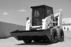 Black and white image of a skid loader in a lot