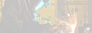 Welder wearing safety mask working with a large piece of equipment with color faded out 3