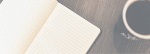 Sepia tone image of an open blank notebook next to a mug of black coffee