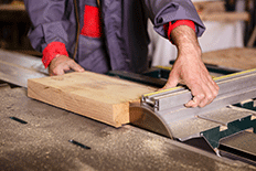 Color image of a man using a woodworking table saw